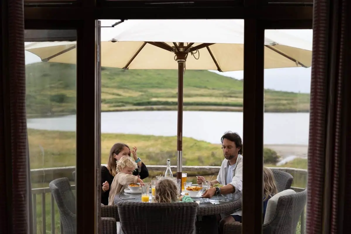 A family eating lunch beneath a parasol overlooking the lagoon at Hell Bay Hotel