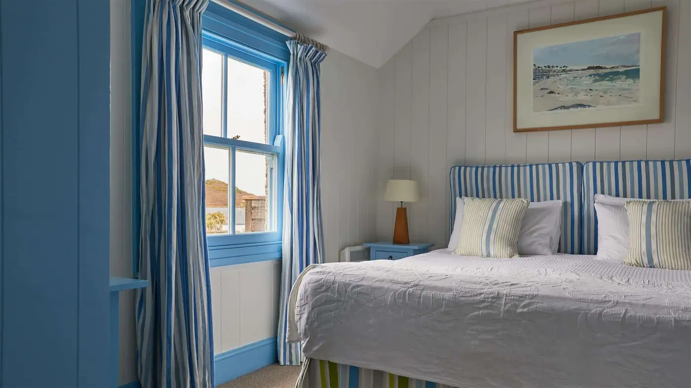 A hotel bedroom with king size bed and blue striped soft furnishings