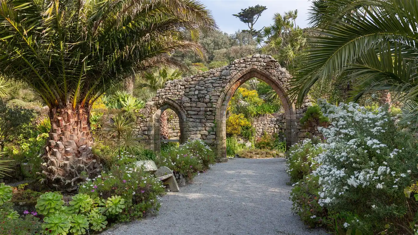Hisyoric abbey arches in Tresco Abbey Garden surrounded by green subtropical planting and flowers