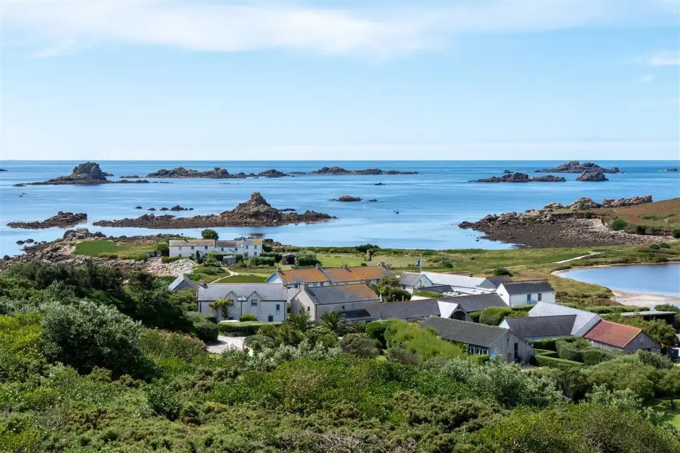 Aerial image of Hell Bay Hotel in the foreground with blue ocean and rocks in the background
