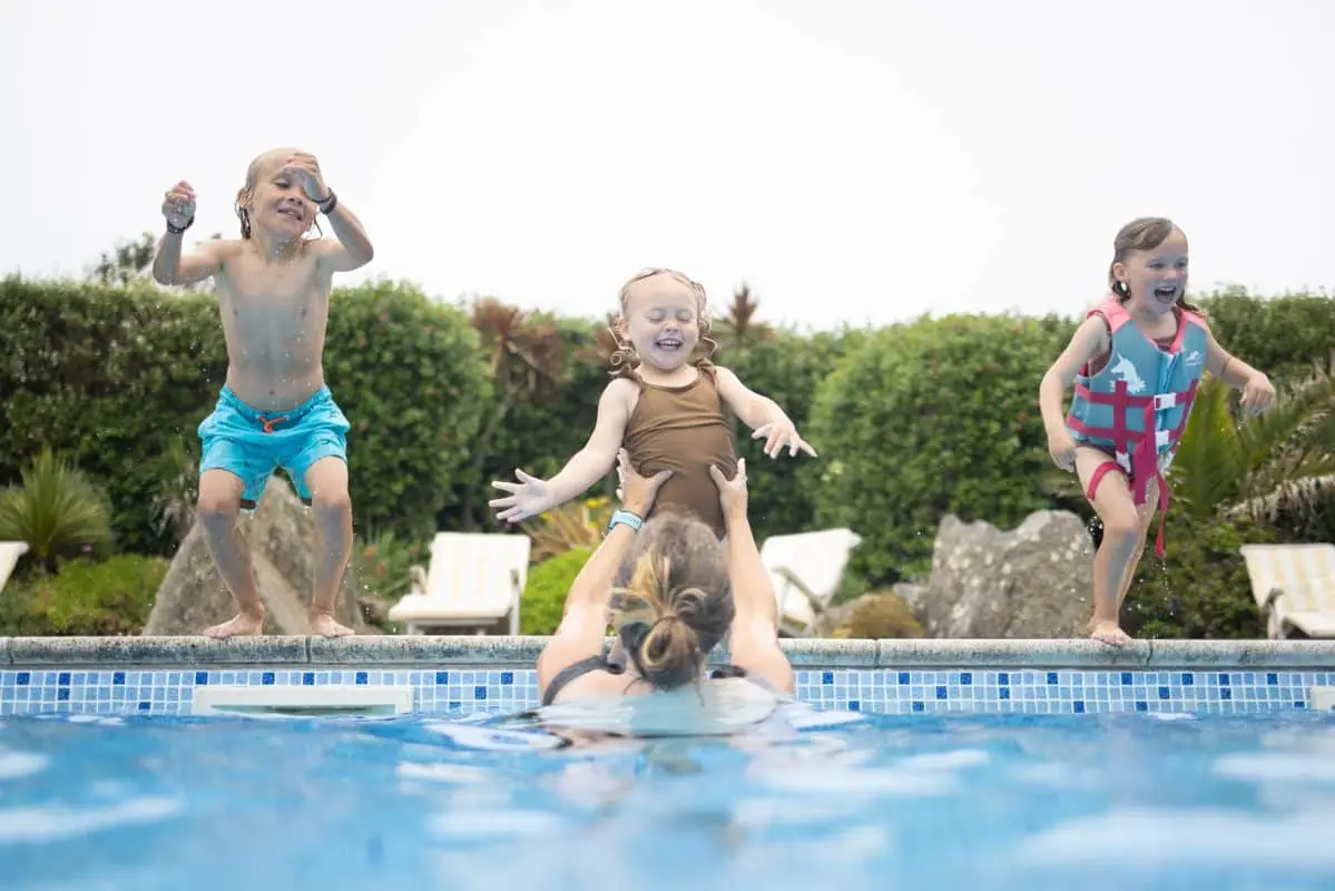 Three happy children jumping into their mother's arms in the swimming pool at Hell Bay Hotel